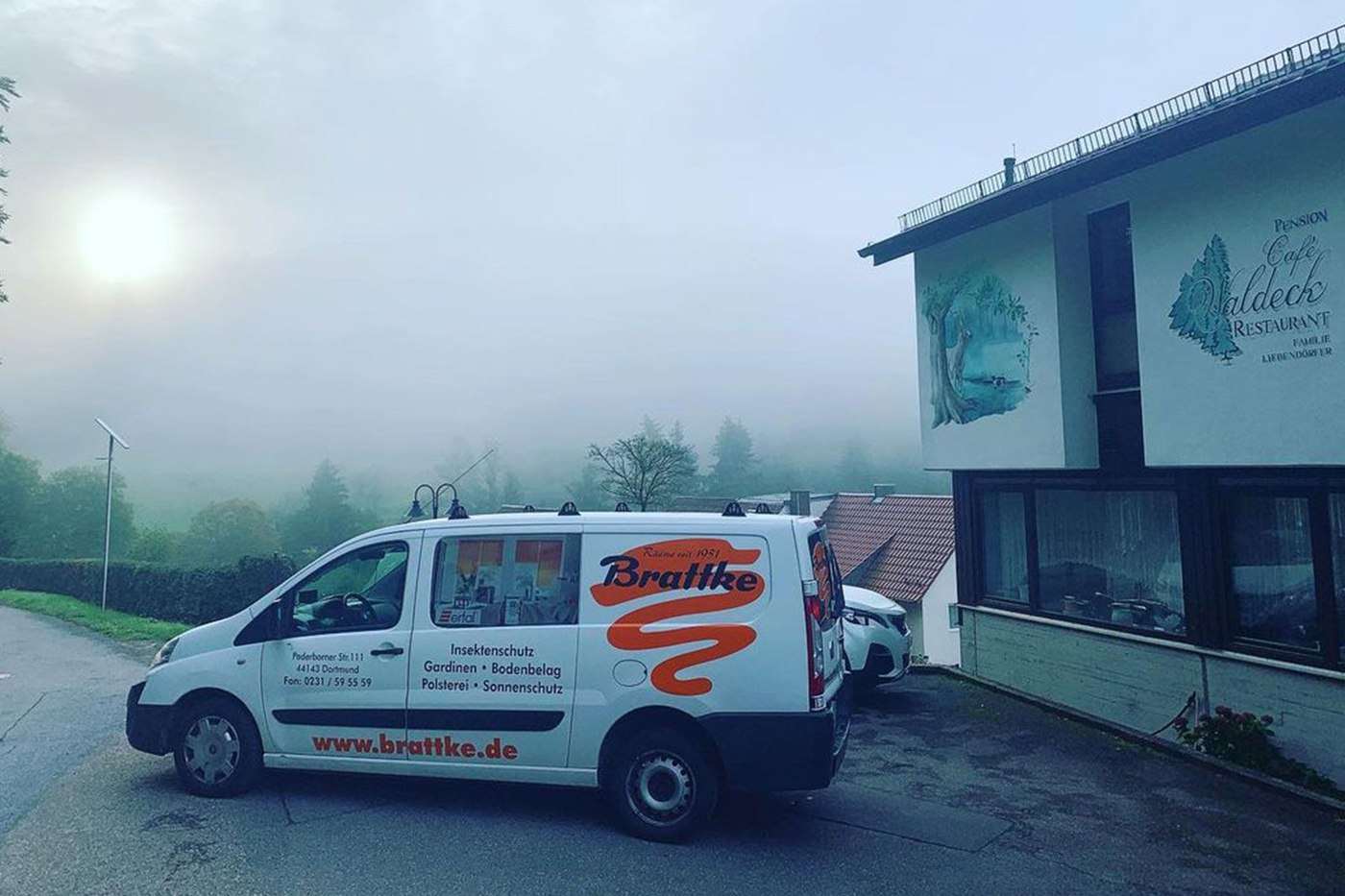Der weiße Firmenwagen der Raumausstattung Brattke, früh morgens im Nebel geparkt